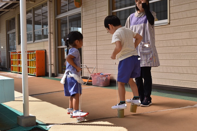 竹ぽっくりをする幼児