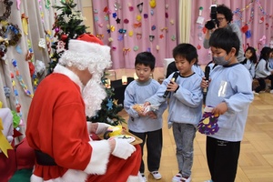 サンタクロースにクッキーとミルクを渡す園児