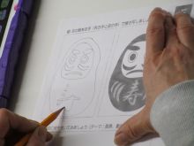 写真:利き手と反対の手でお題「だるま」を描いている様子