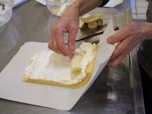 写真:生地に生クリームとバナナを巻いているところ