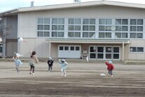 小学校で凧揚げをする園児たち
