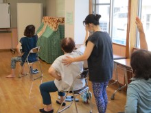 写真：背泳ぎのように腕を後ろに大きく回す動きを講師が指導している様子